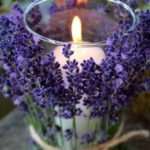 vela branca, tipo de 7 dias, grossa, colocada em porta vela de cristal envolvido em flores de lavanda delicadamente amarradas com fios de ráfia.Ao centro da mesa o efeito é delicado e luminoso.
