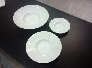 Três pratos de porcelana branca fundos com as bordas largas, colocados juntos com tamanhos diferentes. Os modelos são iguais mas os tamanhos não.