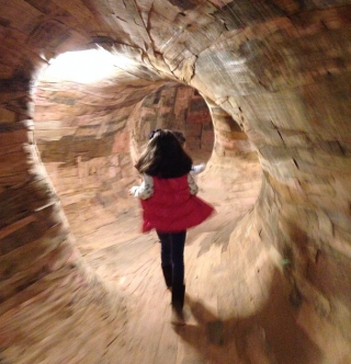menina de 7 anos correndo em uma espécie de labirinto feito em madeira.