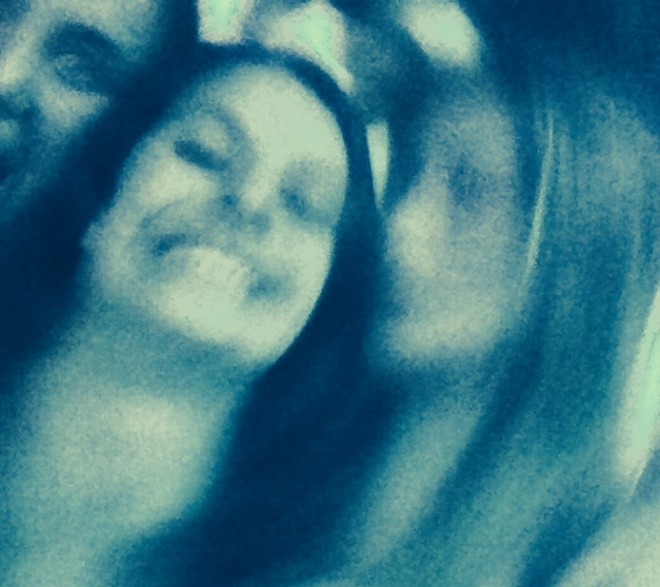 imagem distorcida de rosto jovem sorrindo em movimento. A foto está em tons de azul do claro ao marinho.