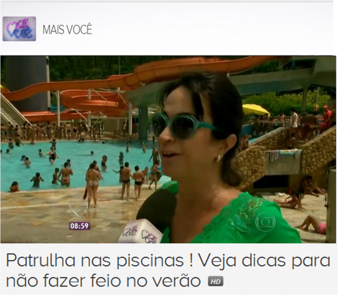 Claudia Matarazzo numa reportagem para o Programa Mais Voce da Rede Globo, está na borda de uma piscina popular, usando uma saia de praia verde e óculos escuros, atrás na imagem uma piscina lotada com milhares de pessoas.
