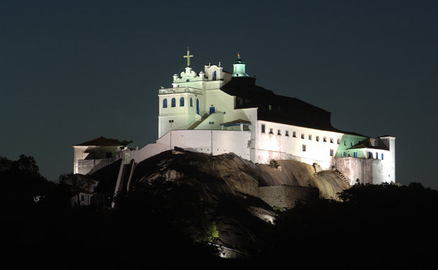 Igreja e Convento de Nossa Senhora da Penha, em Vila Velha, Espirito Santo. Na imagem noturna, aparece toda a construção, na cor branca no topo de um monte sobre as pedras e apenas uma escada de muitos degraus.