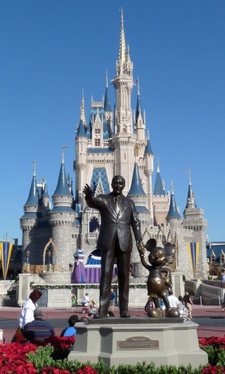 Foto da Disneylandia com os castelos ao fundo e a frente a estátua em bronze do Walt Disney e o Mickey.