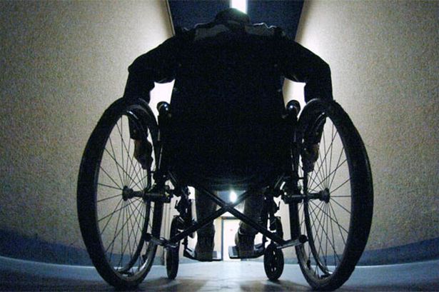 Imagem de um corredor de hospital, com um pessoa andando numa cadeira de rodas