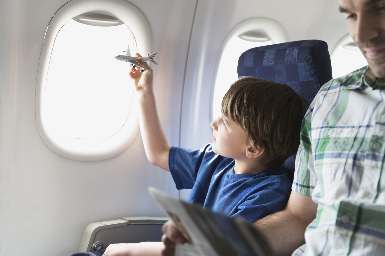 Boy playing with toy plane in airplane