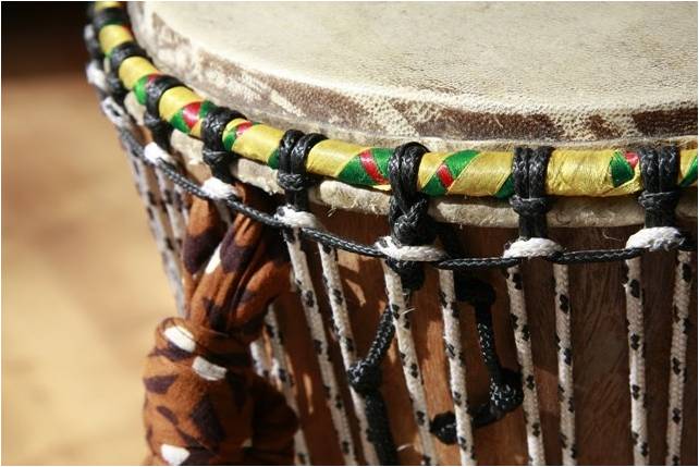 imagem de um atabaque de couro e madeira, com adriças coloridas e cordas para afinação.