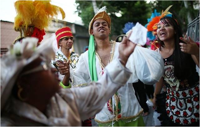 foliões de bloco de rua, vestidos de piratas e alguns foliões brincam na avenida, muitas plumas e adereços coloridos.