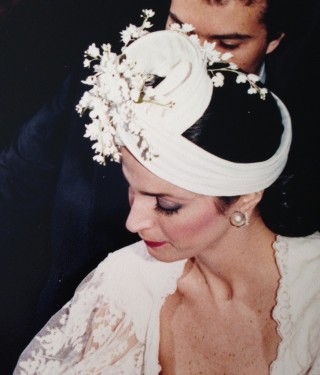 Claudia Matarazzo, no dia do seu casamento, vestida de noiva, usando um turbante branco com pequenas flores brancas.