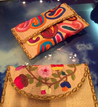 Bolsa feita de palha trançada, com apliques de flores coloridas, pintadas .
