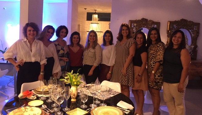 nove mulheres bem vestidas e sorridentes estão em frente a uma mesa posta e Claudia Matarazzo é a terceira da esquerda para a direita.