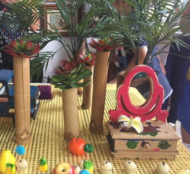 Mesa decorada para festa infantil, com vários objetos (frutas e folhas verdes) compõem o cenário.
