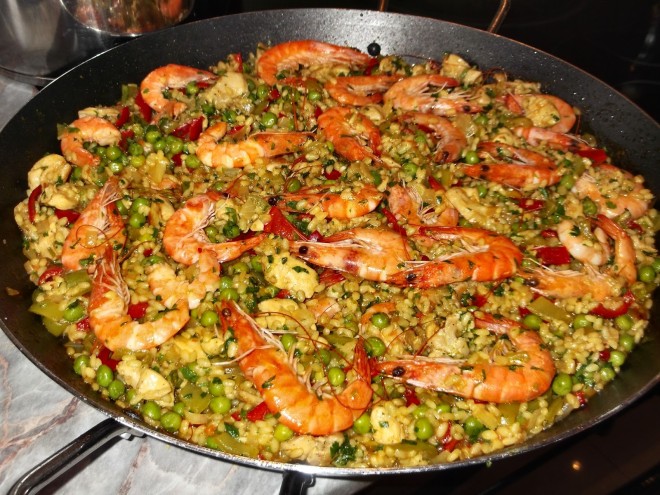 gamela grande, contendo paella que é um prato típico espanhol, que contem arroz e varios frutos do mar, camarões, mariscos e ervilhas, temperos e tomates.