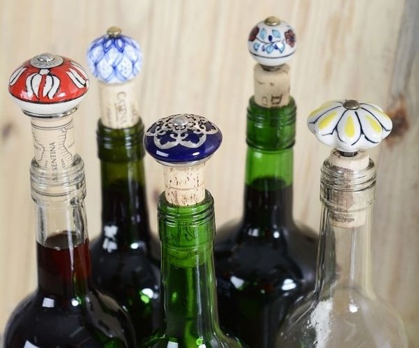 várias garrafas coloridas e transparentes com tampas de rolhas em acabamento de vidro trabalhado - esmaltado ou pintado a mão.