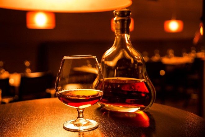 imagem de um copo com um pouco de cognac e ao lado uma garrafa com rolha, com um pouco de cognac.