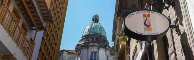 uma foto do centro histórico de Santos com uma cúpula estilo rococó mostrando ao fundo um céu bem azul.