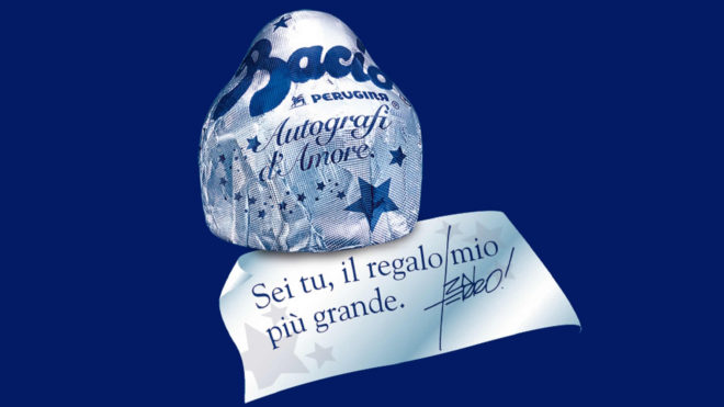 Numa base azul, um bombom do Baccio Perurigini com o famoso bilhetinho que está contido em cada um deles, com mensagens ao Dia dos Namorados.