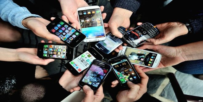 Inúmeros braços, estendidos num círculo, todos segurando nas mãos smartphones, celulares, .