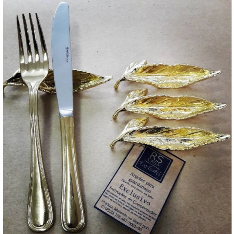 Descanso de talher de mesa, em metal, em forma de folha, com fundo dourado.