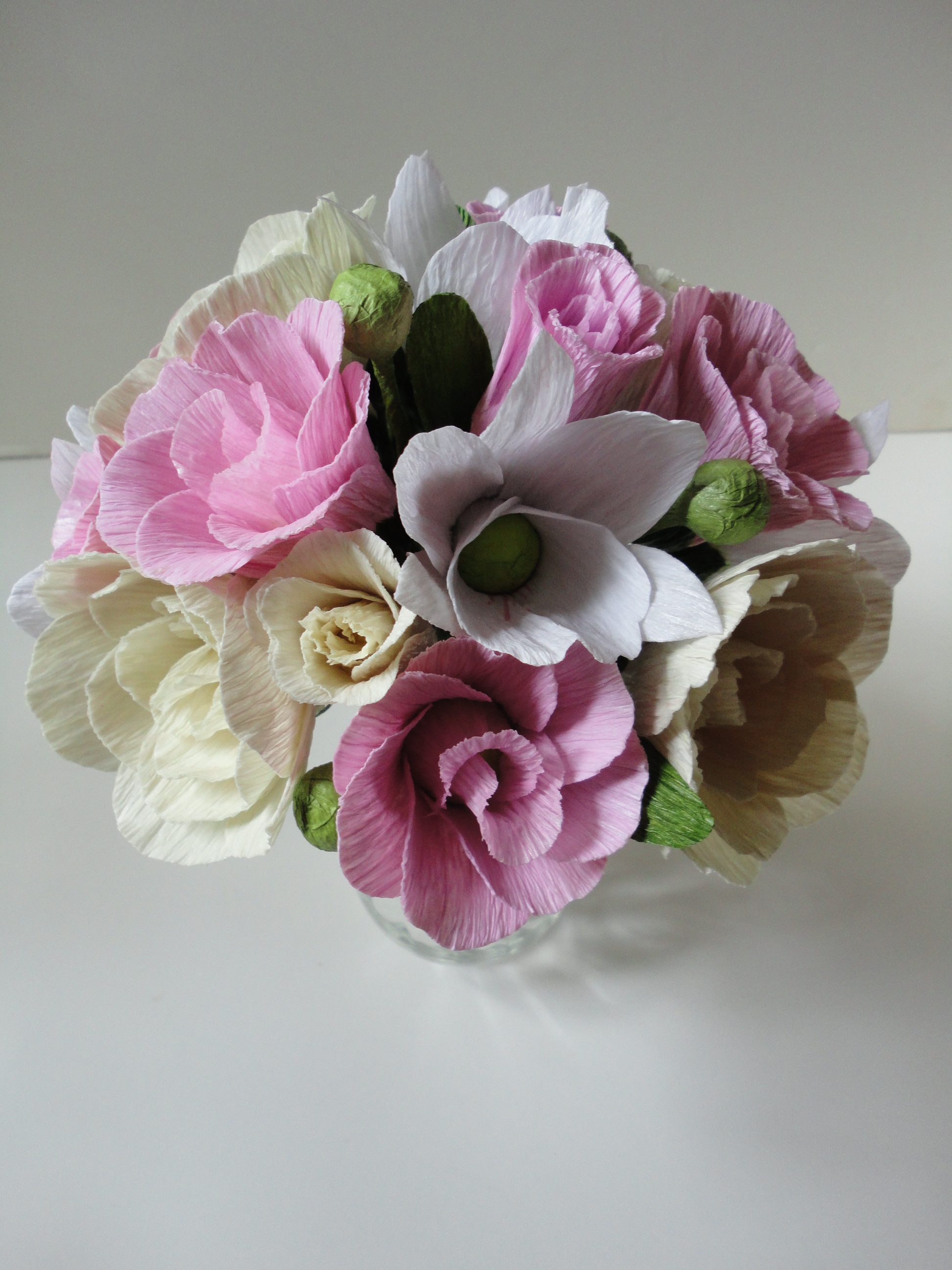 Várias rosas e lisianthios em três cores suaves: cor de rosa claro, creme e branco estão amarrados formando um buquê redondo e harmonioso.