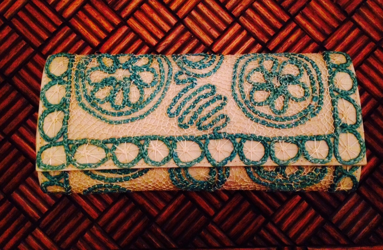 bolsa tipo carteira em palha de buriti cor creme lara delicadamente trançada de forma artesanal como uma renda, combinando com desenho floral também em palha em cor turquesa.