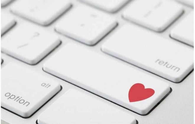 imagem em detalhe de um teclado de notebook, on a tecla "Enter" tem um símbolo do coração, na cor vermelha. Simbolizando que a pessoa está se relacionamento pela internet.