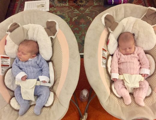 dois bebês com cerca de um mês estão em duas cestas diferentes um vestido de azul outro de cor de rosa e ambos dormem .